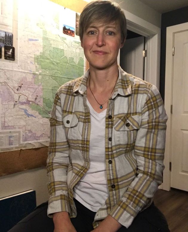 A woman in a plaid shirt is sitting in front of a map.