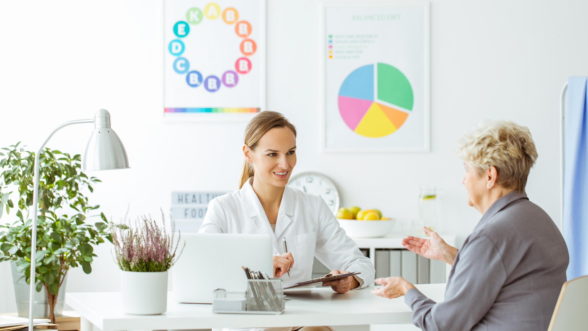 A doctor is talking to an elderly woman at a desk.