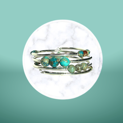 A silver ring with turquoise beads is stacked on top of each other.