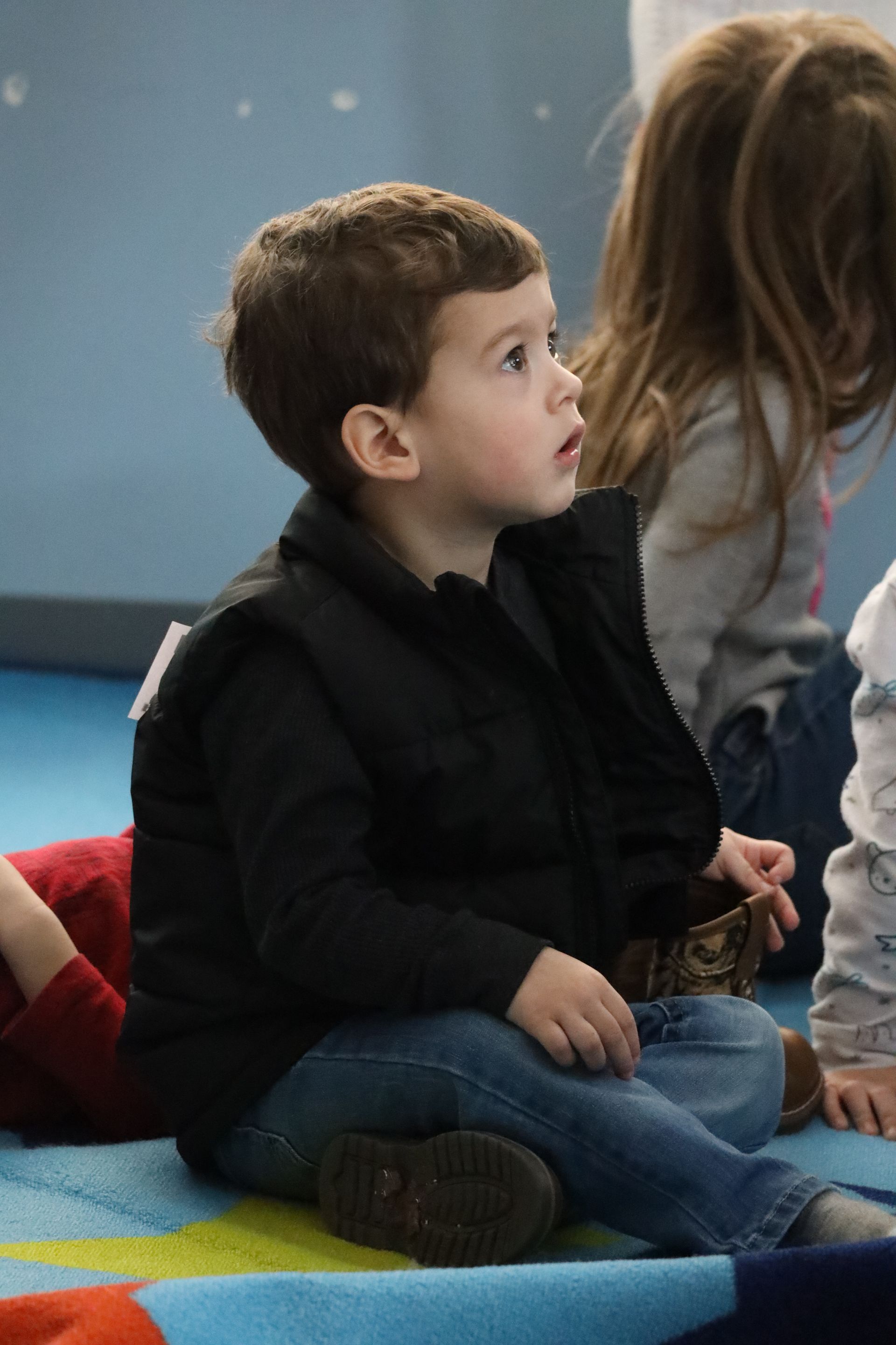 a young boy is standing in front of a toy shelf .