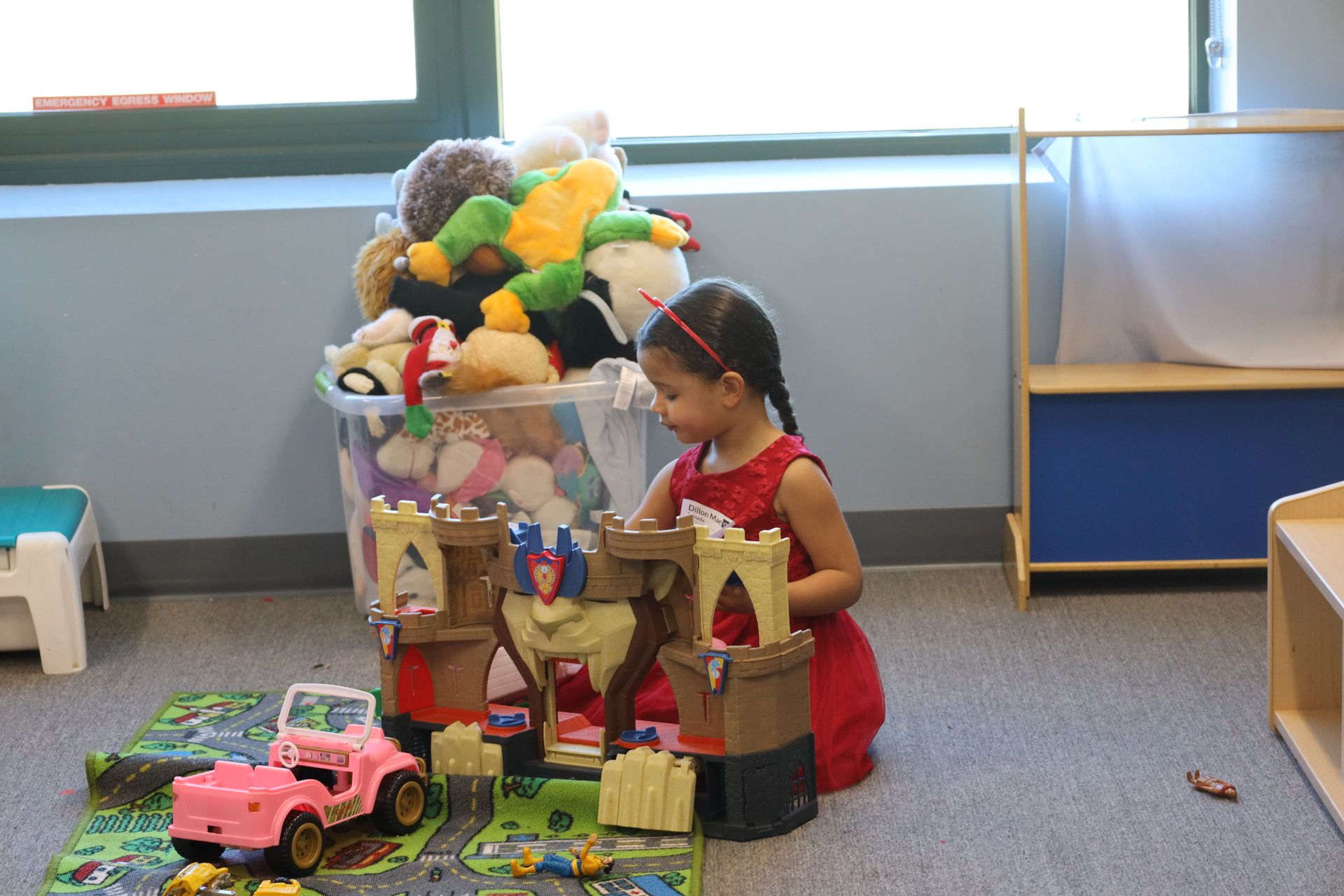 a little girl in a red dress is playing with a toy castle