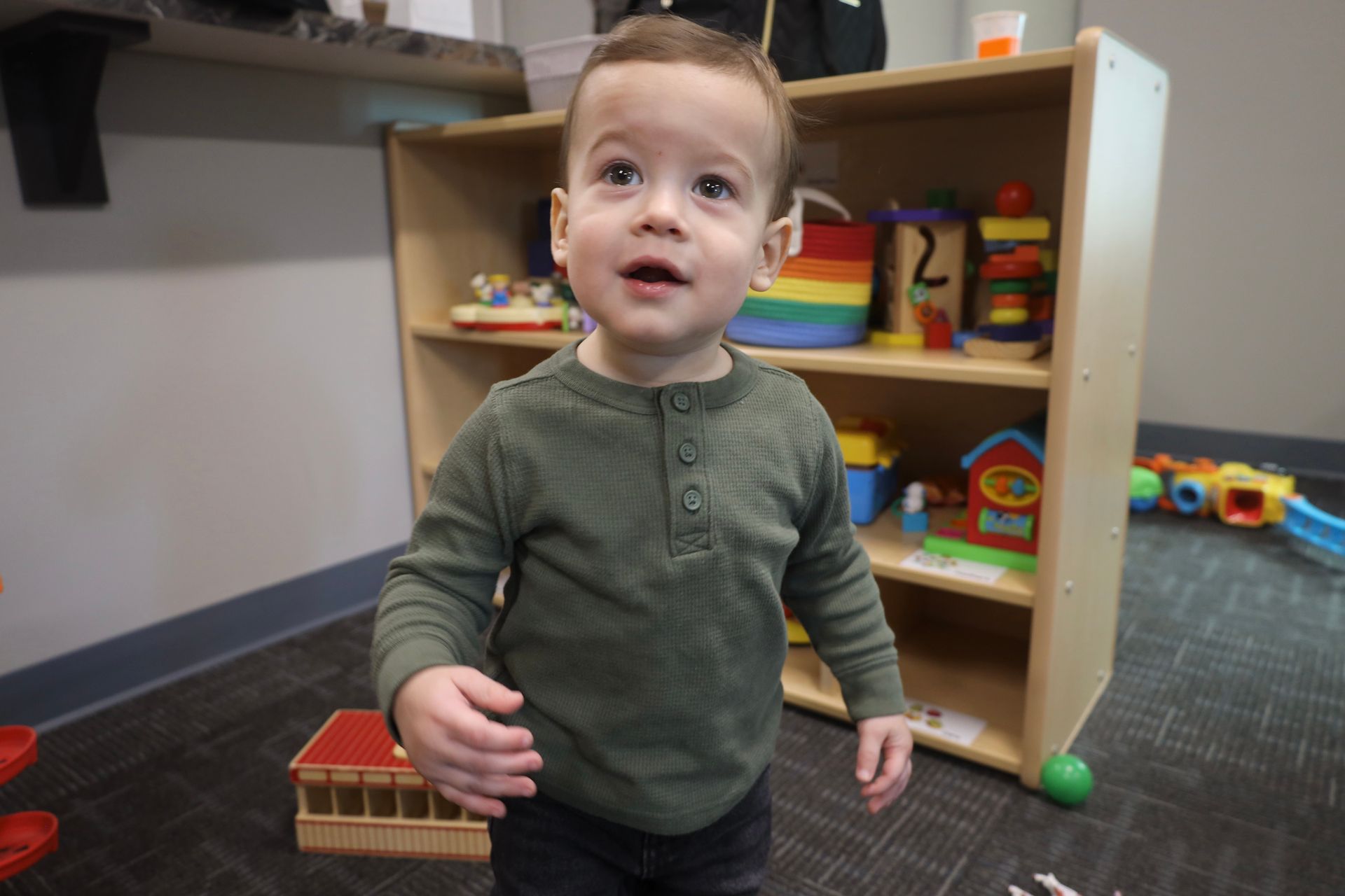 a young boy is standing in front of a toy shelf .