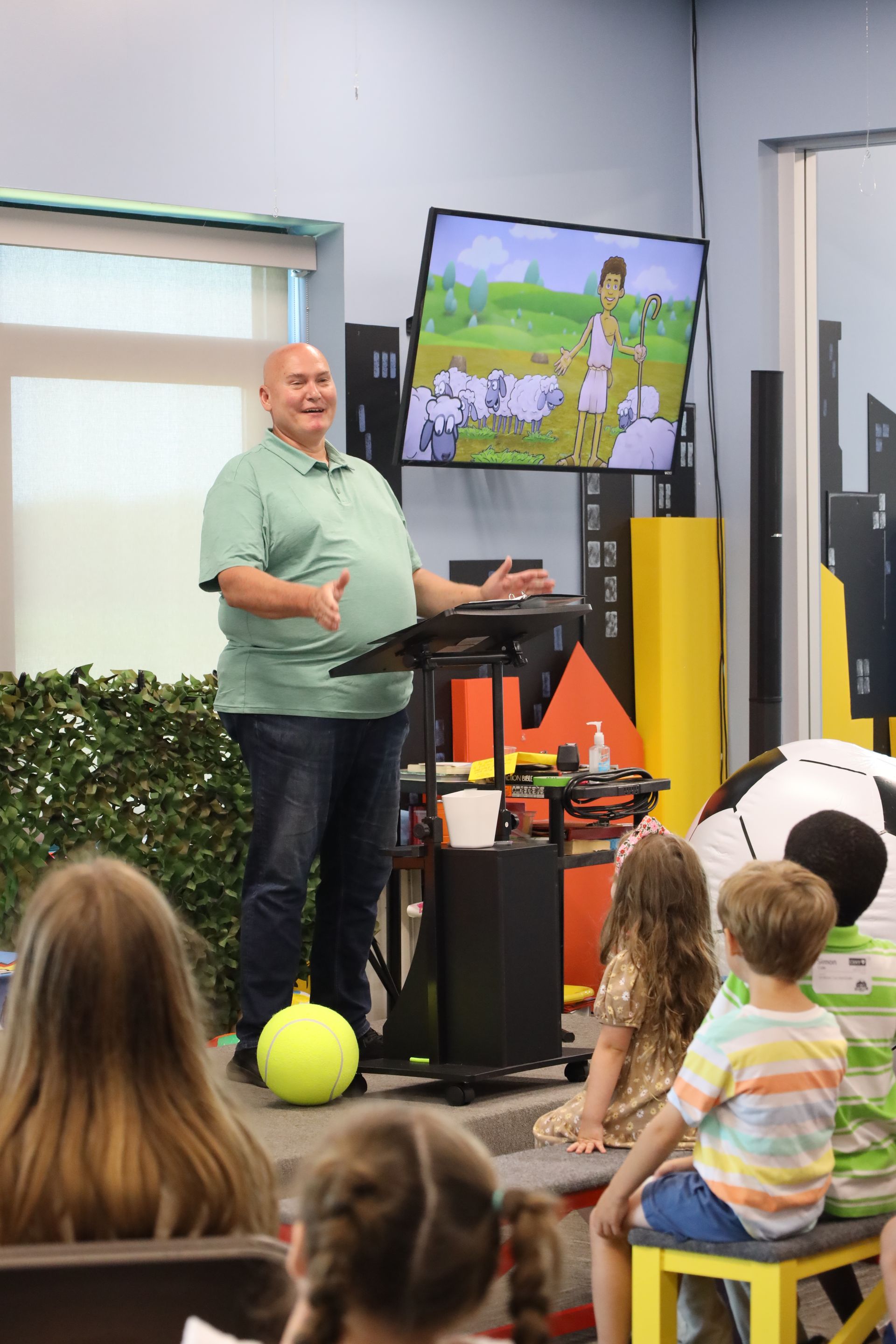 a woman is talking to a group of children sitting in chairs .