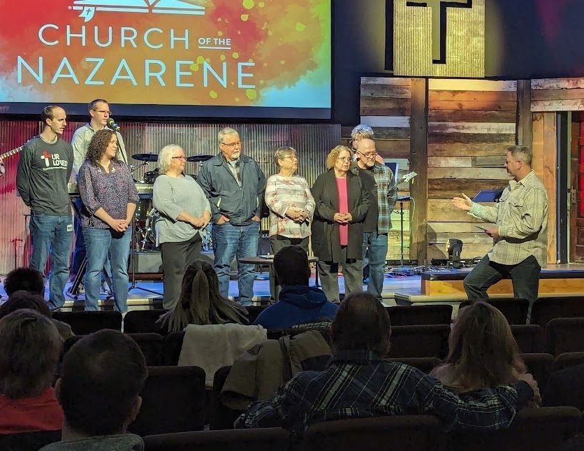 a group of people are standing in front of a large screen. Church of the Nazarene