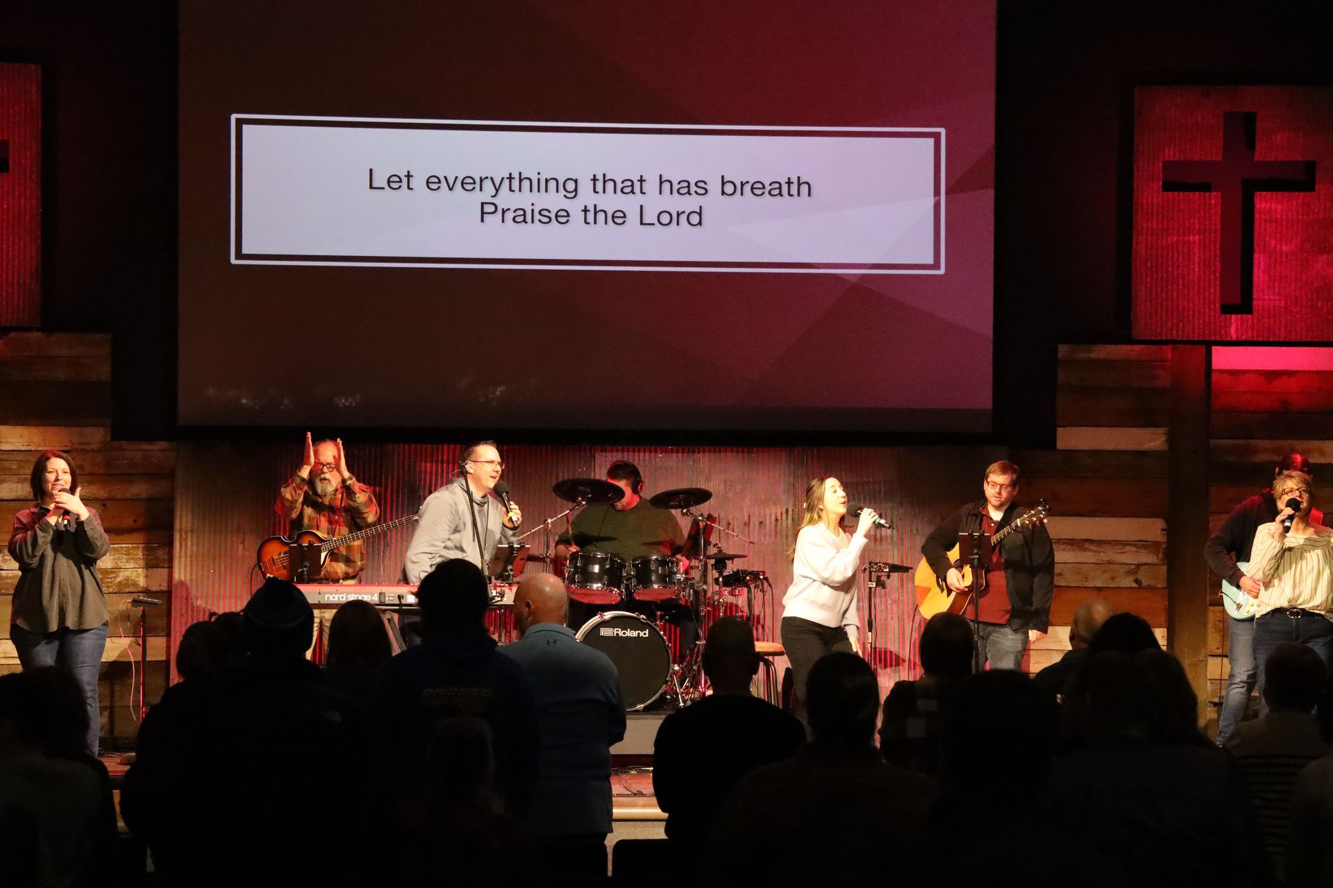 a group of people are singing in front of a large screen .