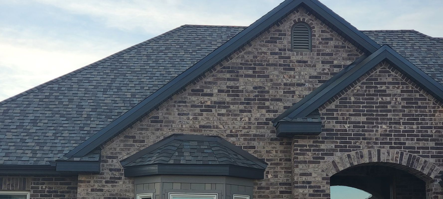 A brick house with a gray roof and chimneys
