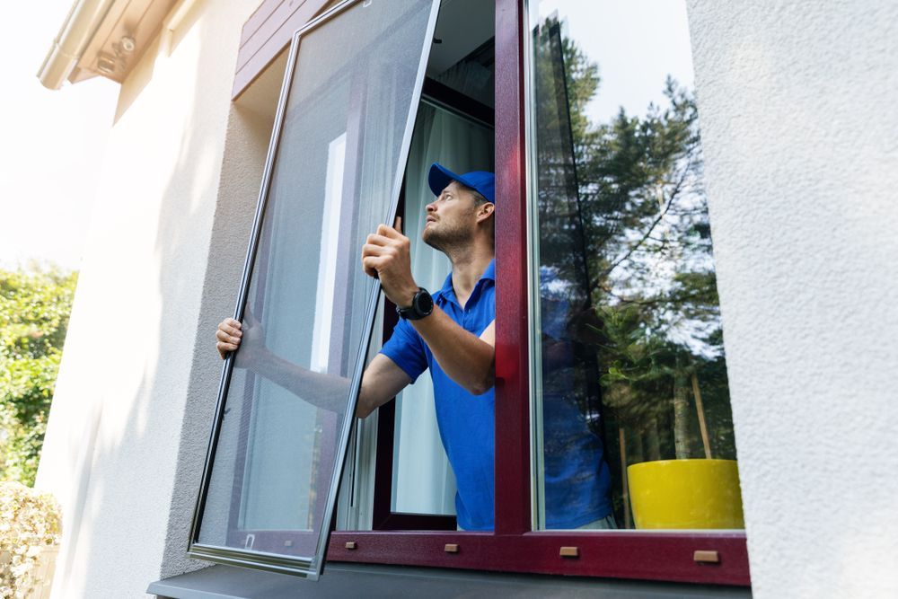 A man is installing a mosquito screen on a window.
