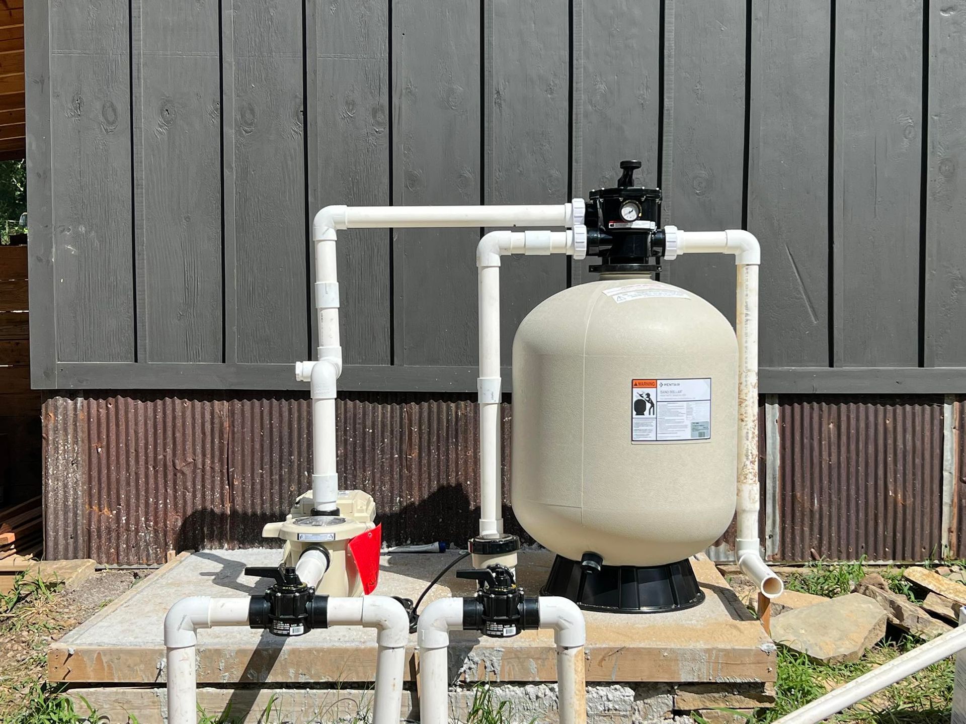 A swimming pool filter is sitting on top of a concrete platform.