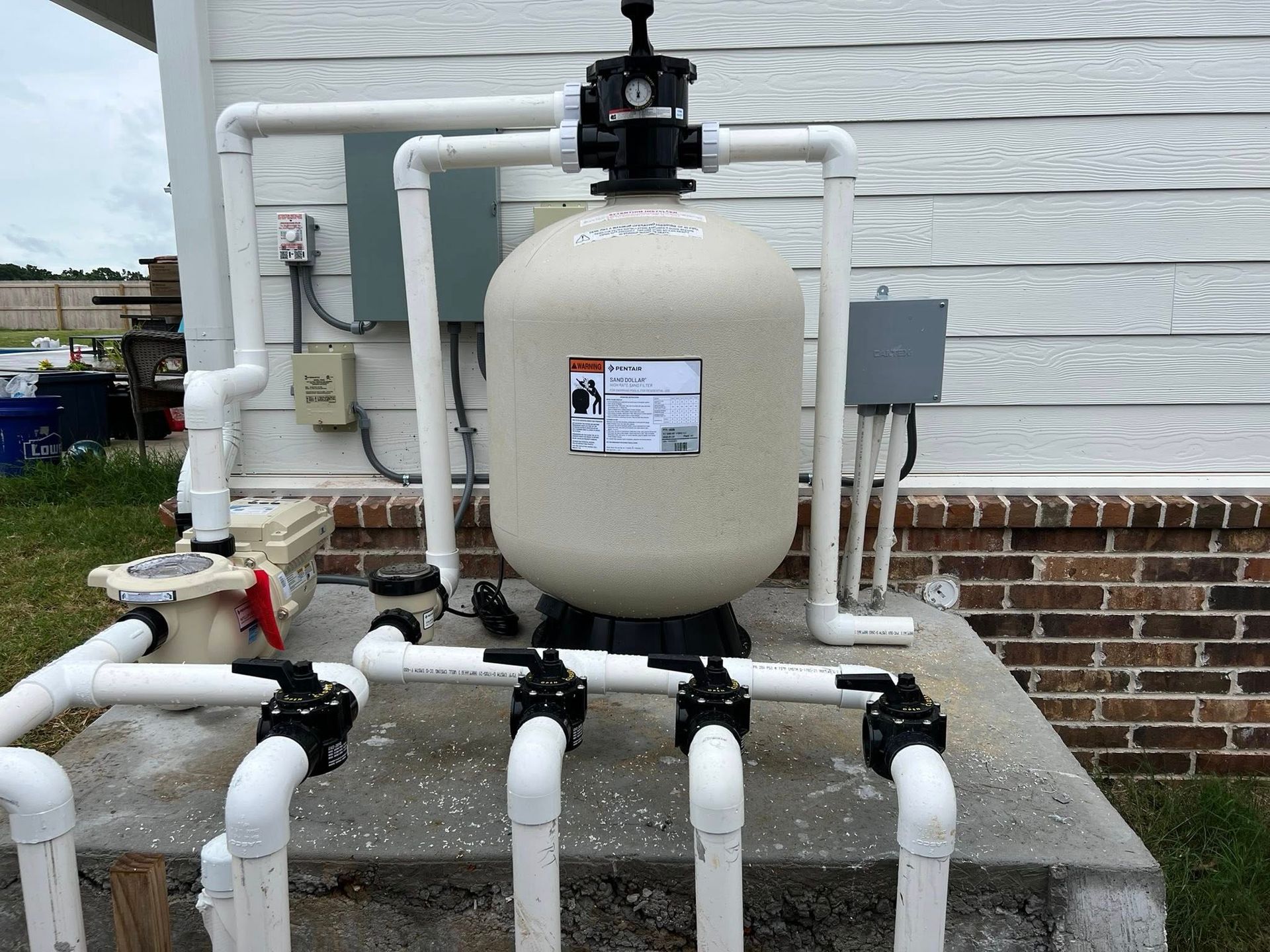 A swimming pool filter is sitting on top of a concrete platform next to a brick building.