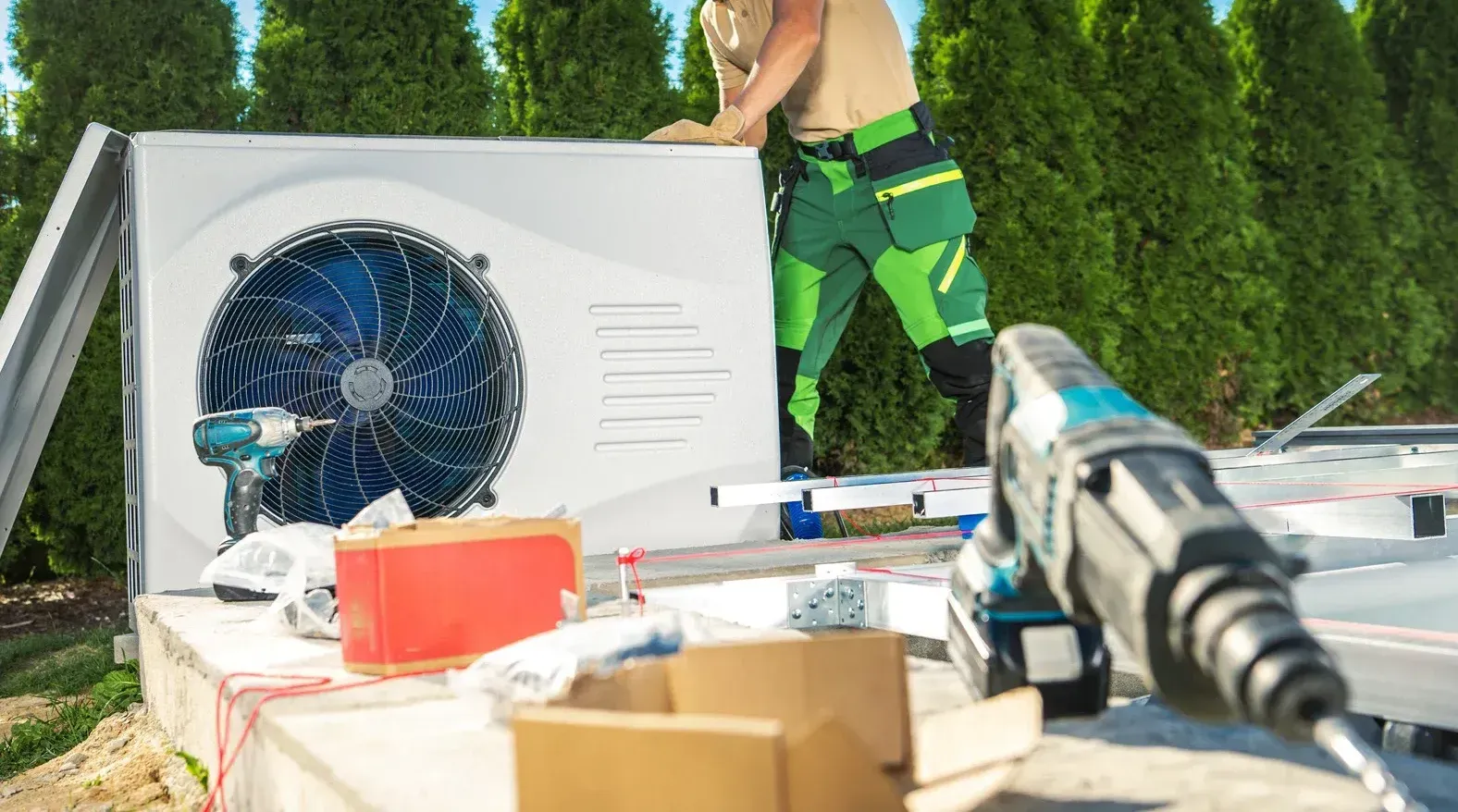 A man is installing a heat pump in a backyard.