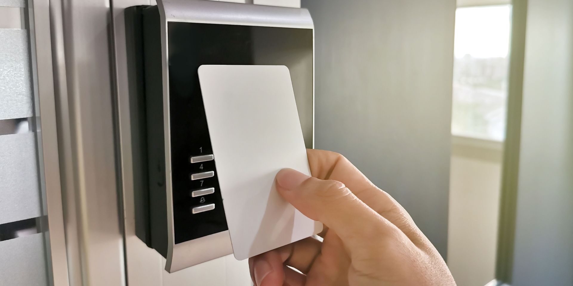 Person holding a white access card to a security device on a door.