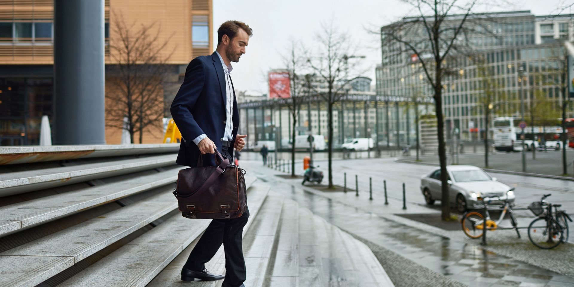 A man in a suit is walking down stairs with a briefcase.