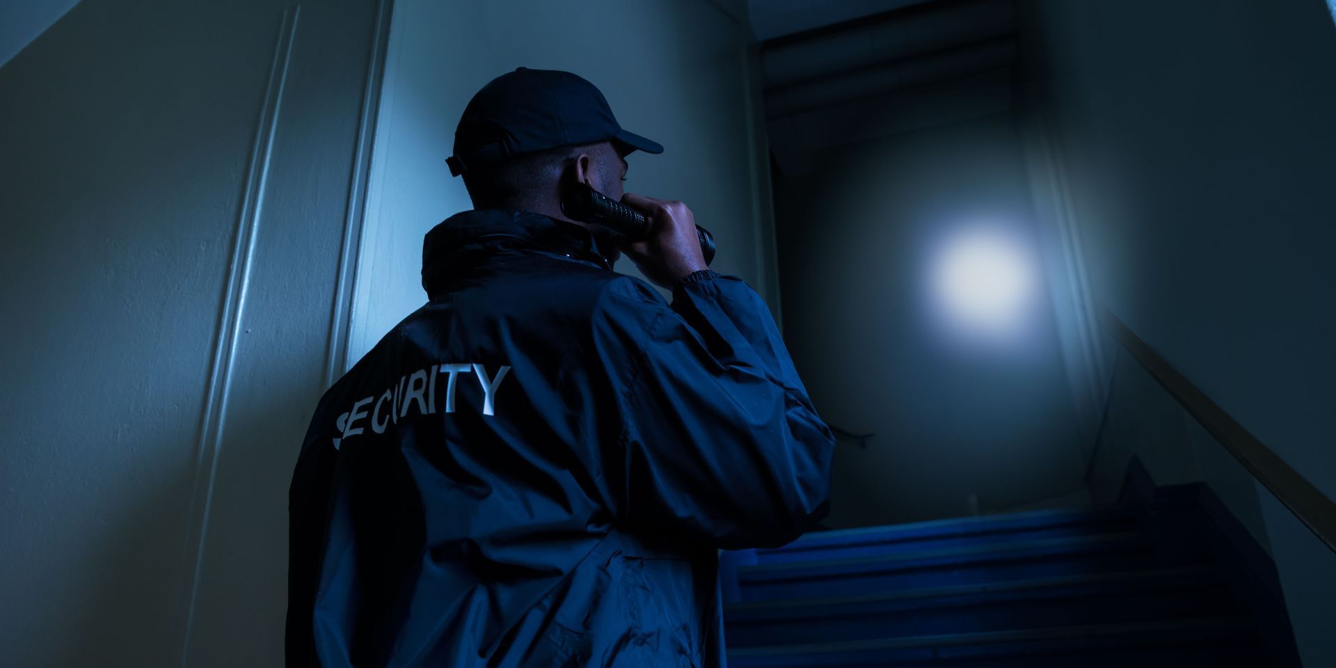 Security guard in dark stairwell, talking into a radio. The word