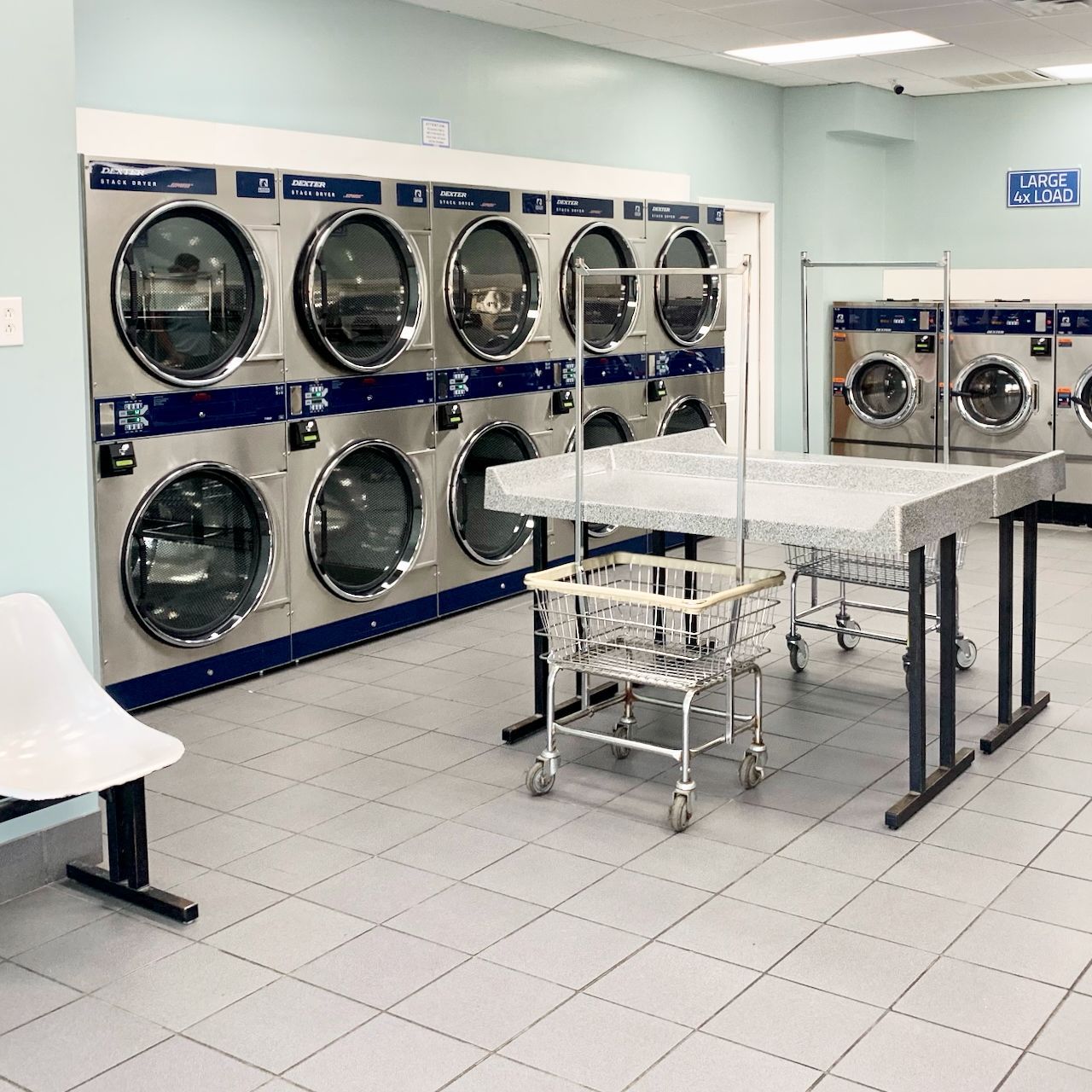 Laundromat with wall of washers & dryers, folding tables & rolling laundry baskets