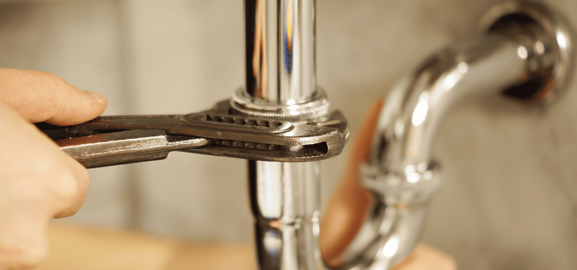 Homeowner checking on a plumbing pipe with a spanner