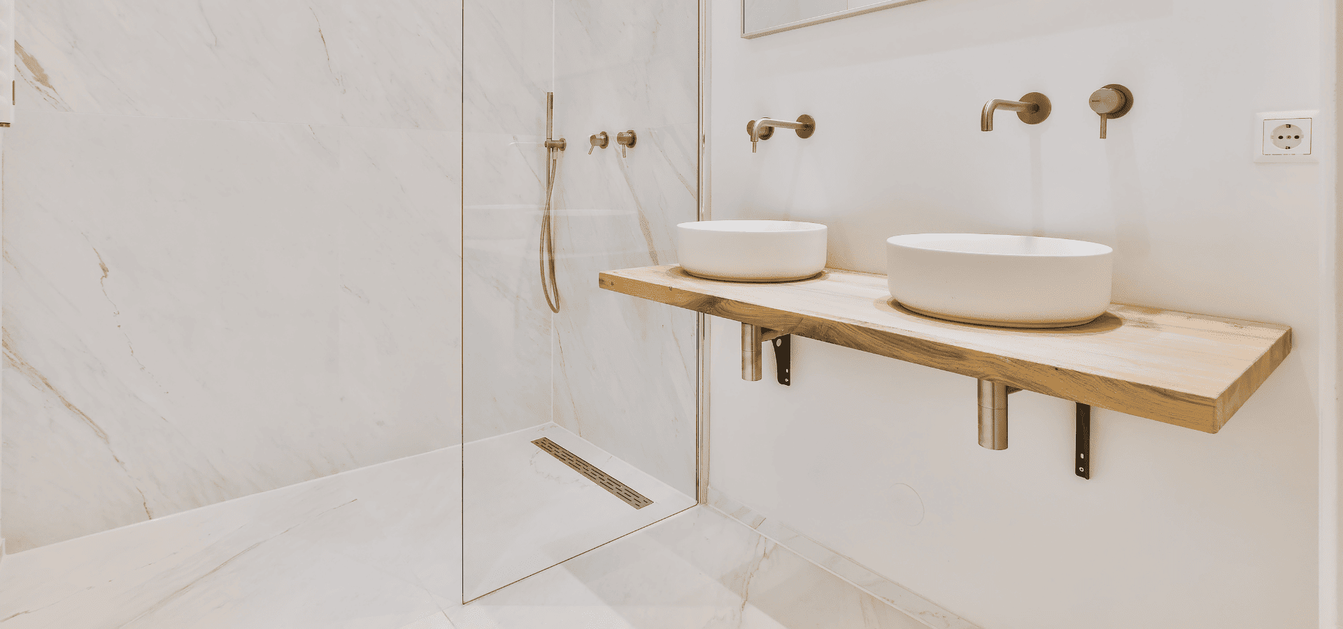 A modern, minimalist luxury bathroom with a curbless, spacious shower and roll-under ready sinks