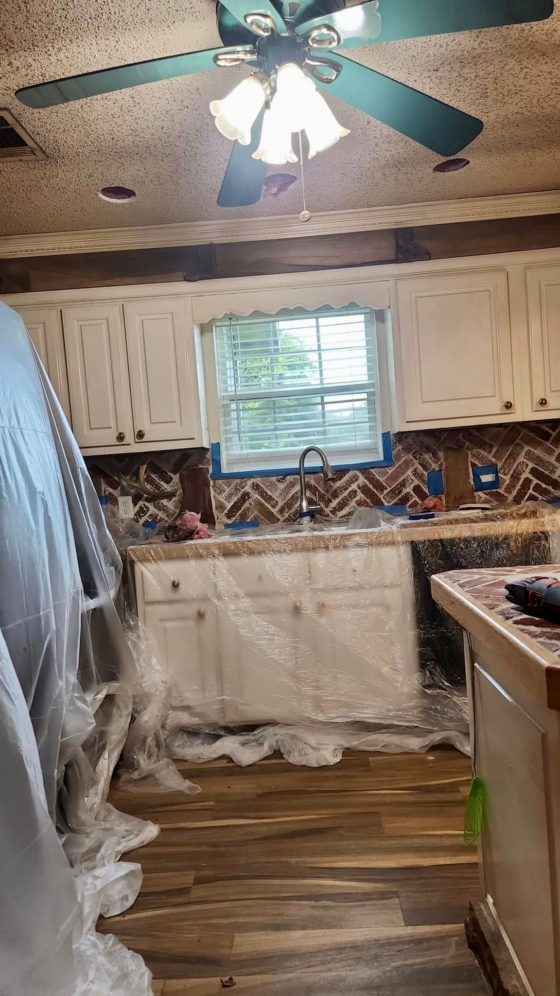 A kitchen with white cabinets and a ceiling fan.