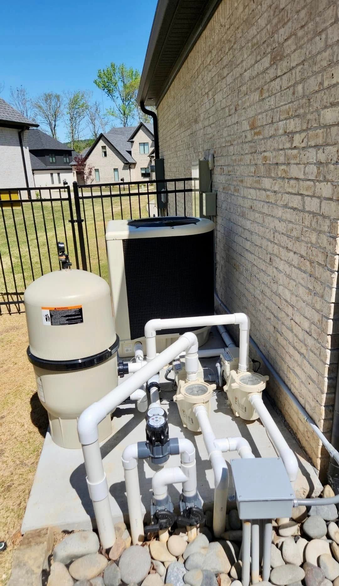 A swimming pool pump is sitting on the side of a brick building.