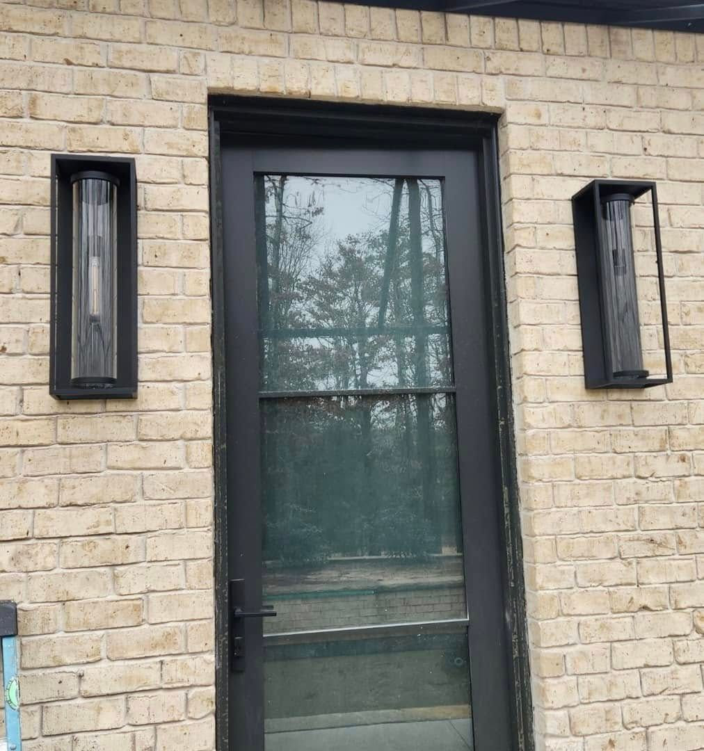 A brick building with a black door and two lights on the side