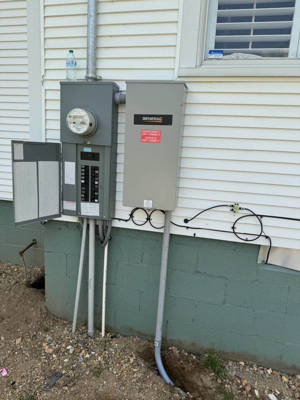 An electrical box is attached to the side of a house