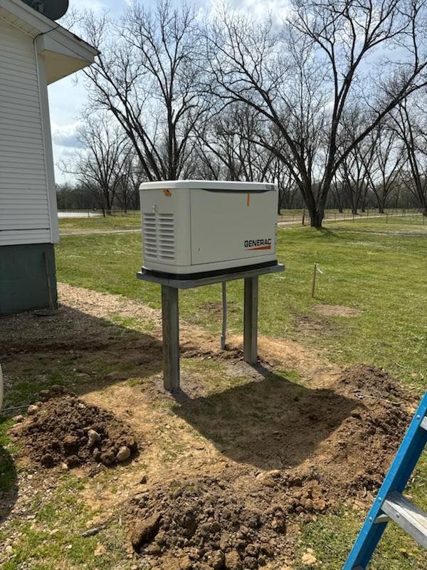 A generator is sitting on top of a metal stand in the dirt in front of a house.