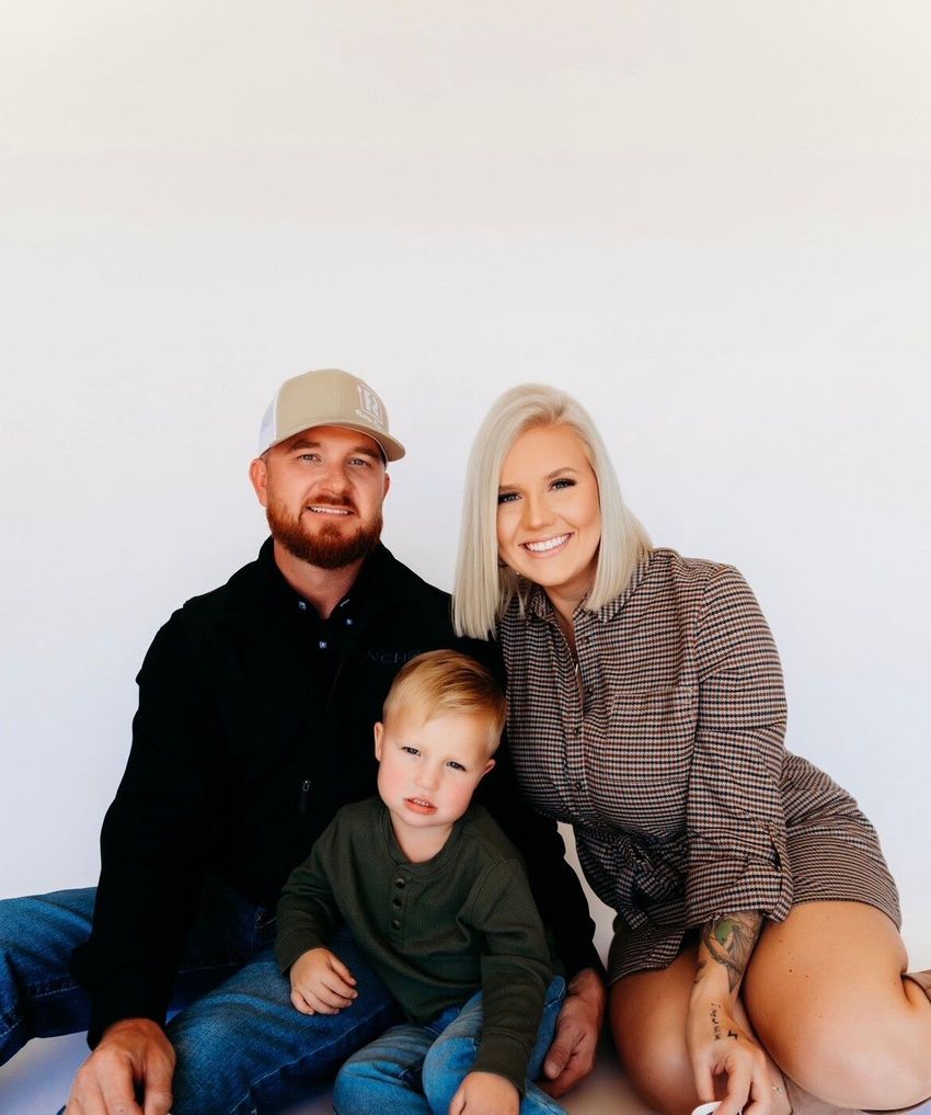 A man , woman and child are posing for a picture while sitting on the floor.