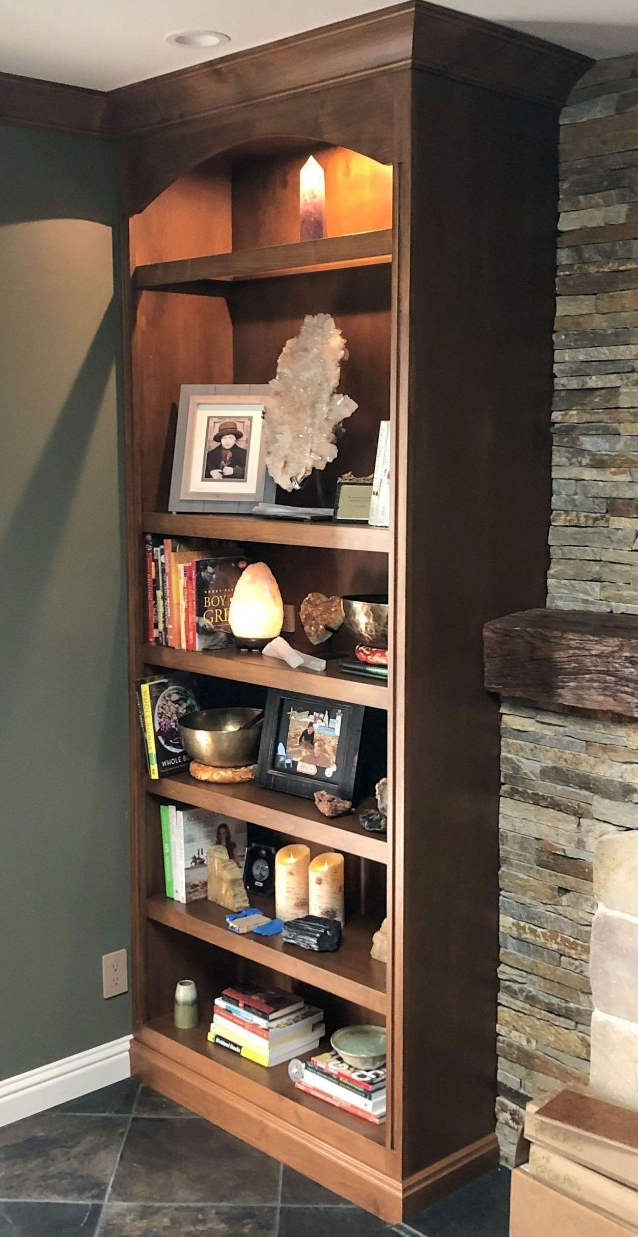 A wooden bookshelf in a living room next to a fireplace.