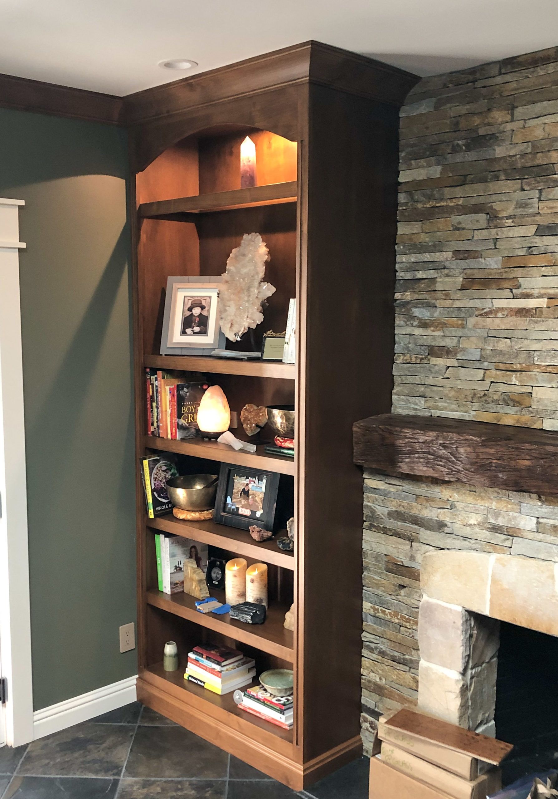 A bookshelf in a living room next to a fireplace.