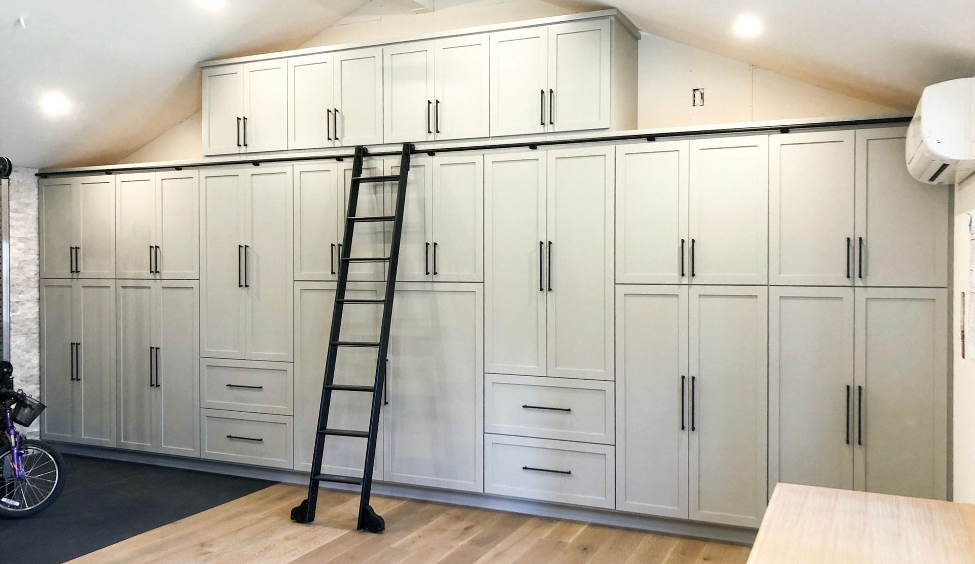 A large room with lots of cabinets and drawers and a ladder.