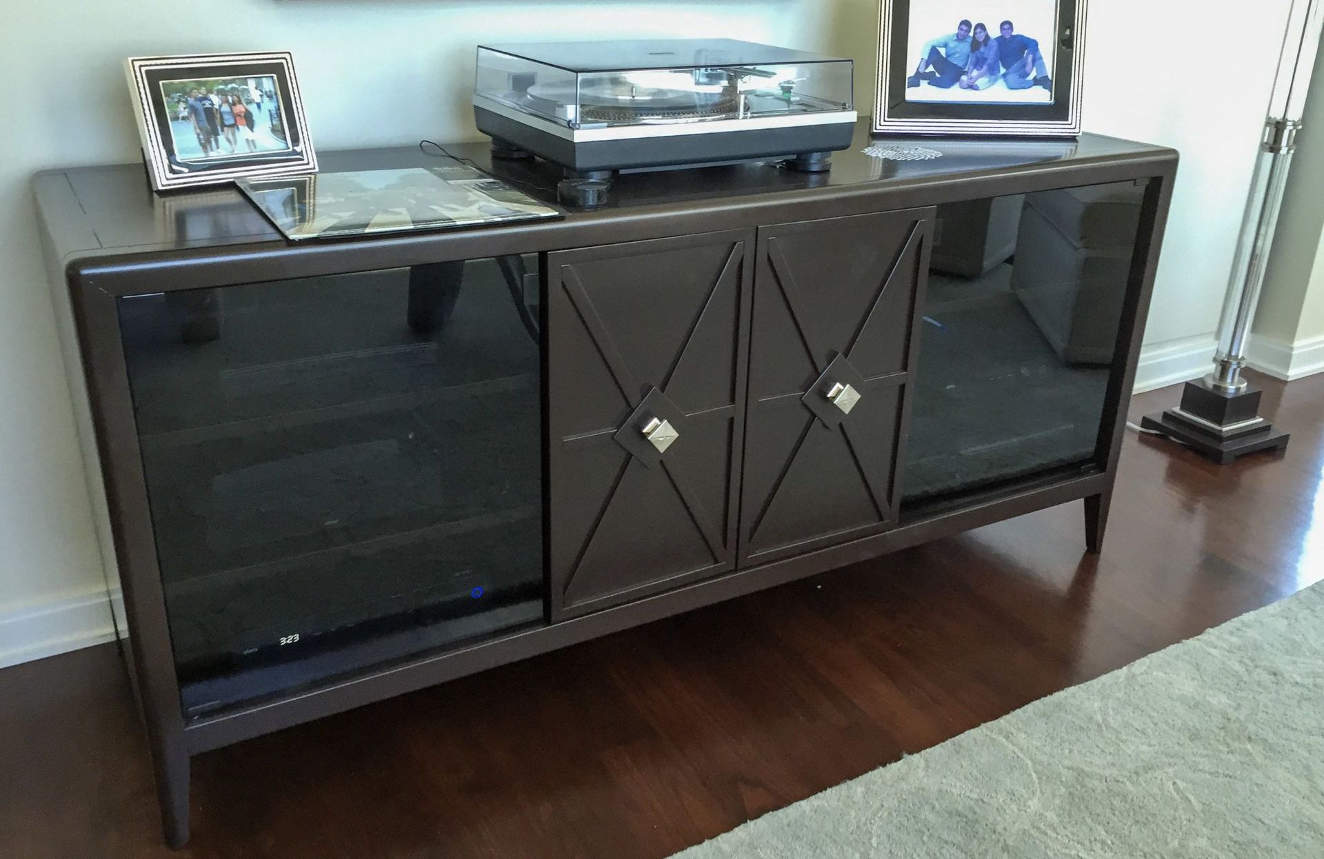 A record player is sitting on top of a dresser in a living room