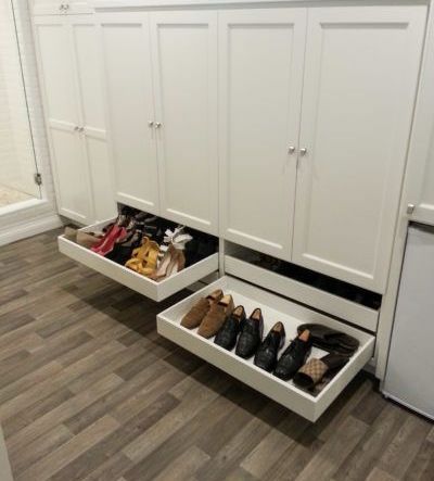 Two drawers filled with shoes are pulled out of a cabinet