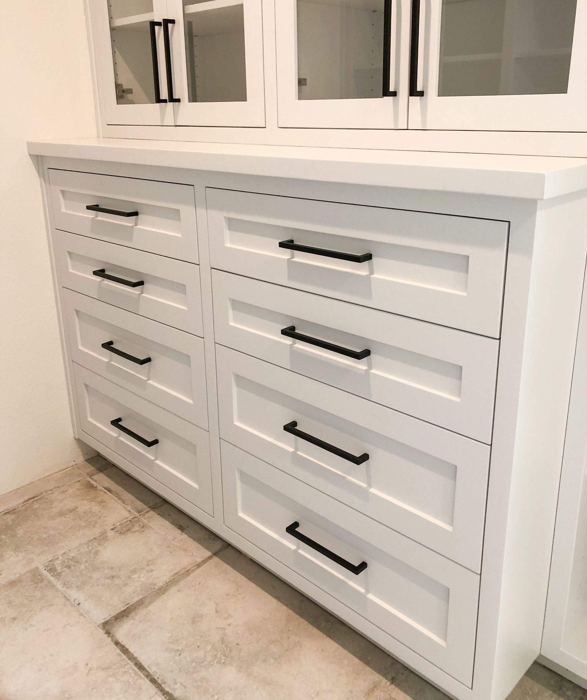 A white dresser with black handles in a room