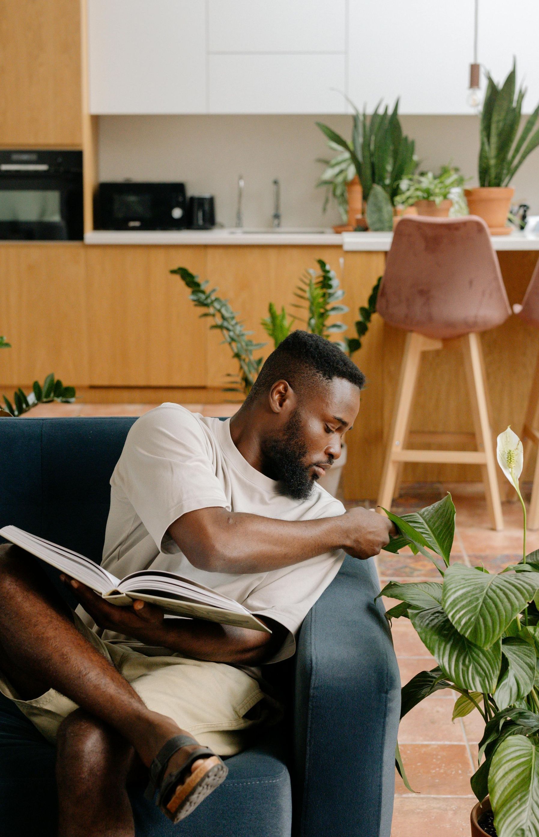 A man is sitting on a couch reading a book.