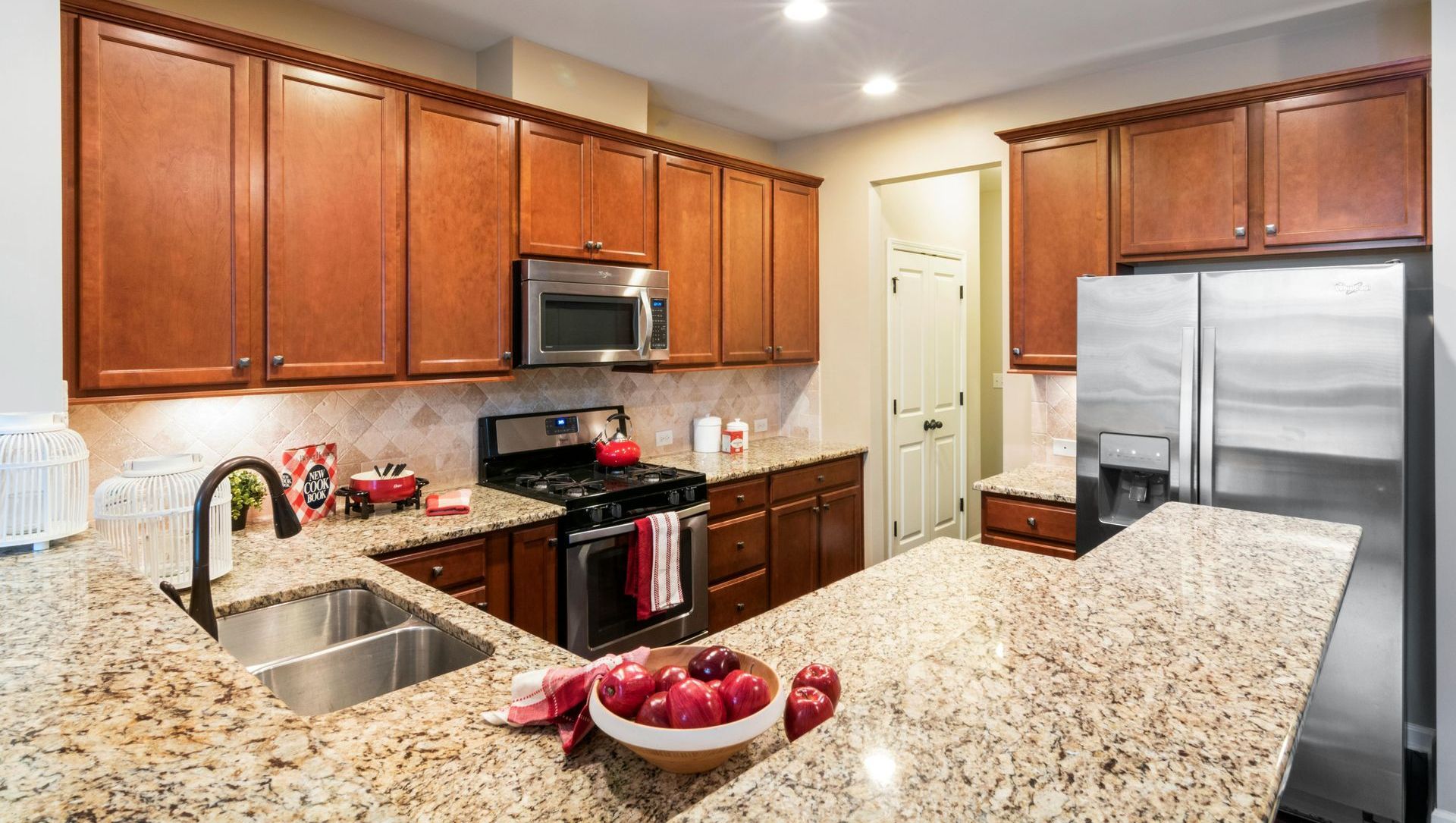 A kitchen with granite counter tops , stainless steel appliances , and wooden cabinets.