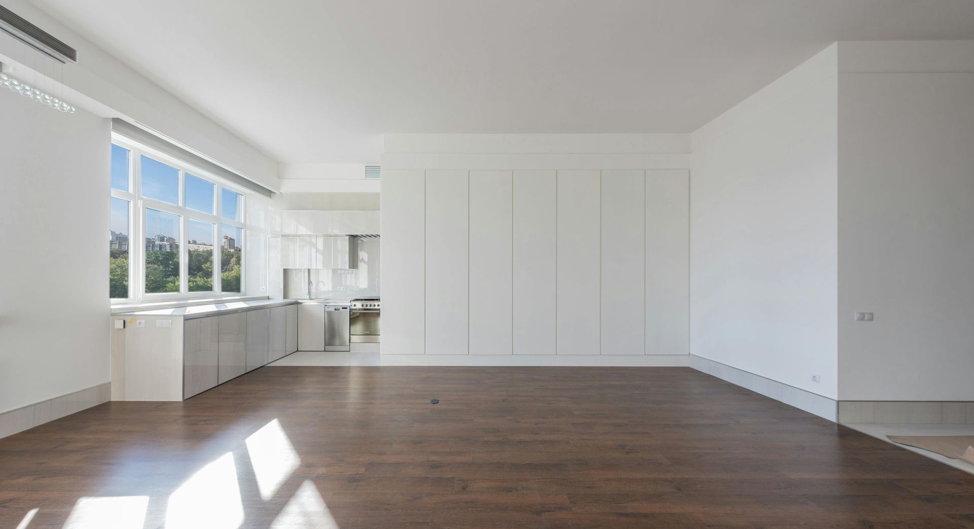 An empty living room with hardwood floors and white walls.