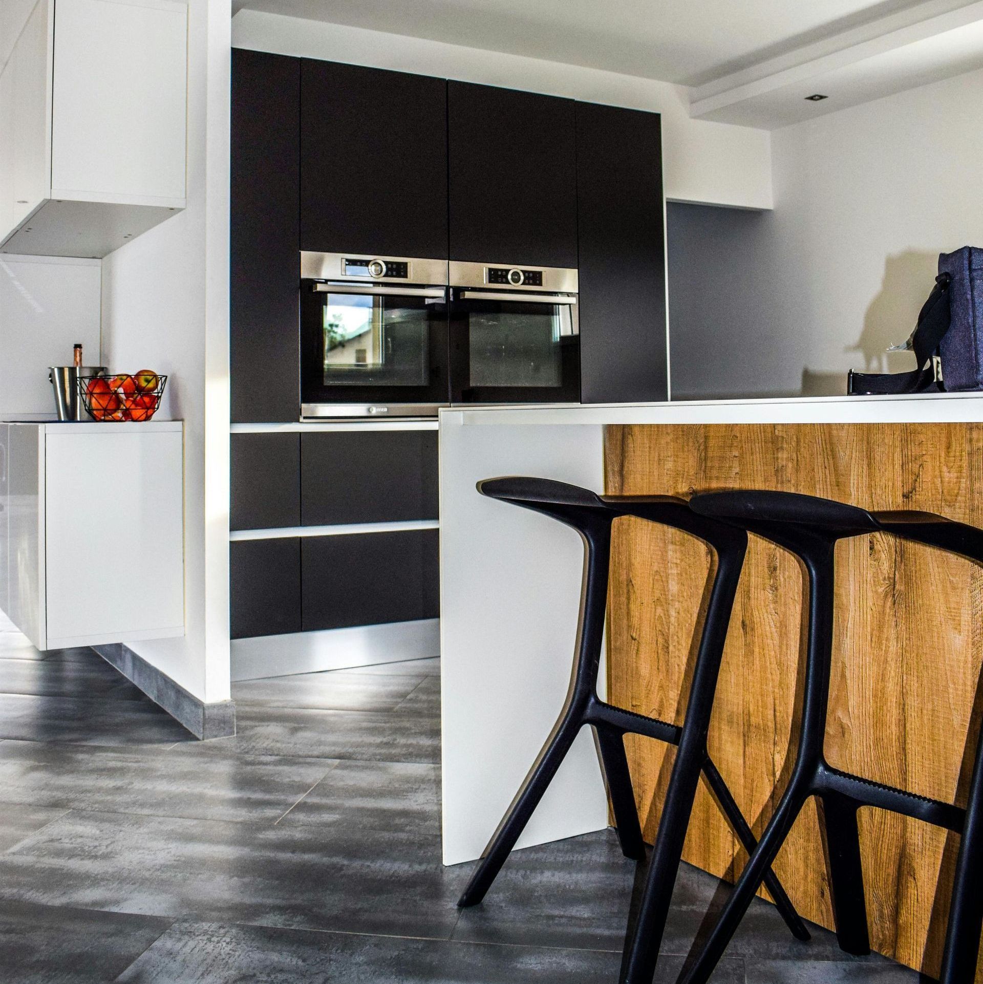 A kitchen with black stools and a white counter