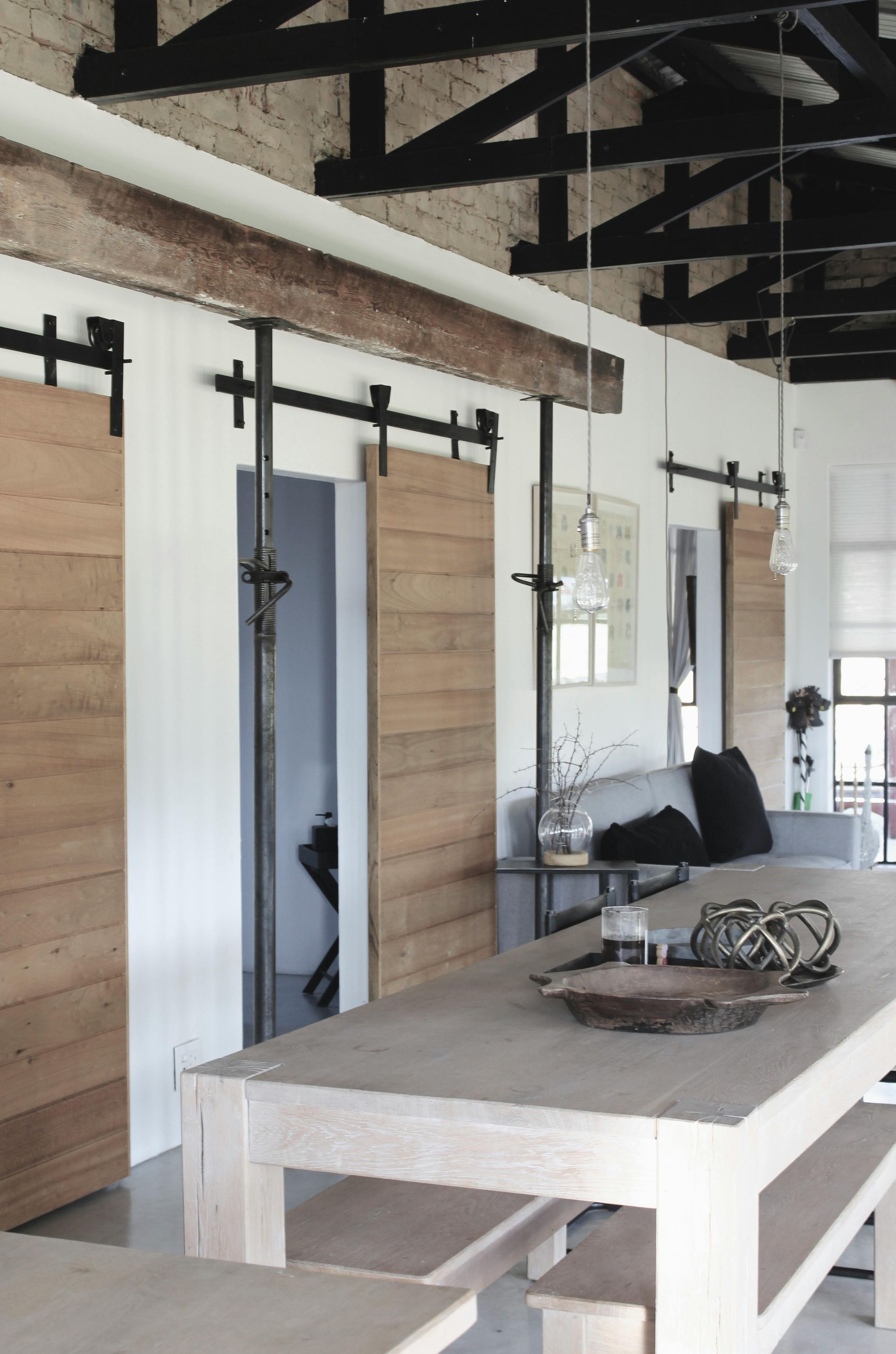 A dining room with a table and benches and sliding barn doors