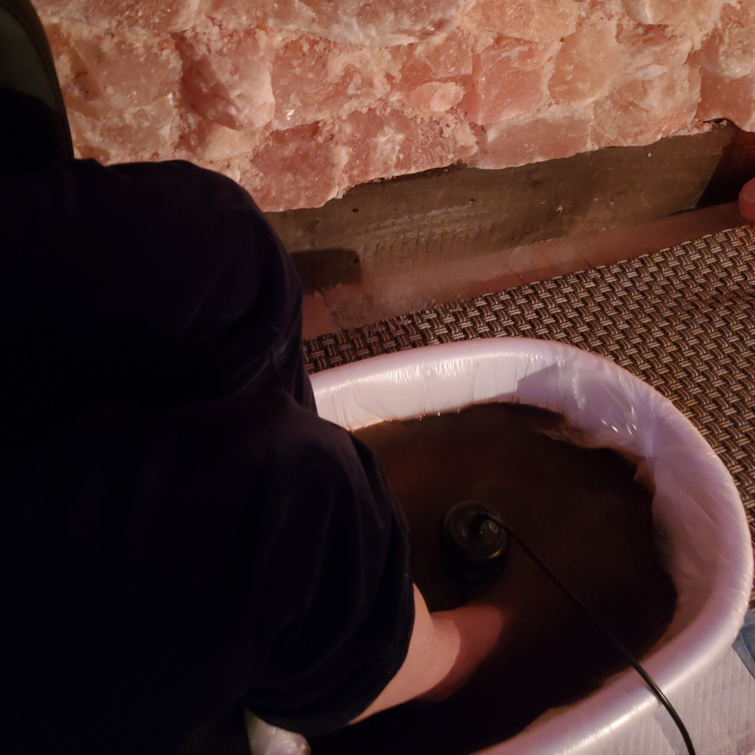A person is washing their feet in a bowl of water
