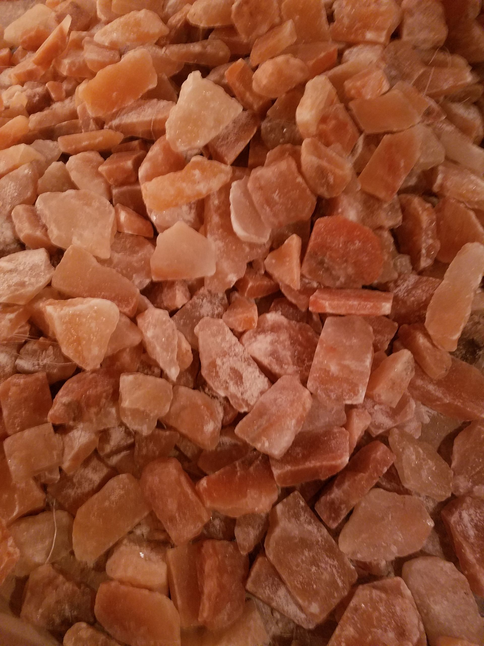 Pile of roughly-cut, orange-pink Himalayan salt chunks.