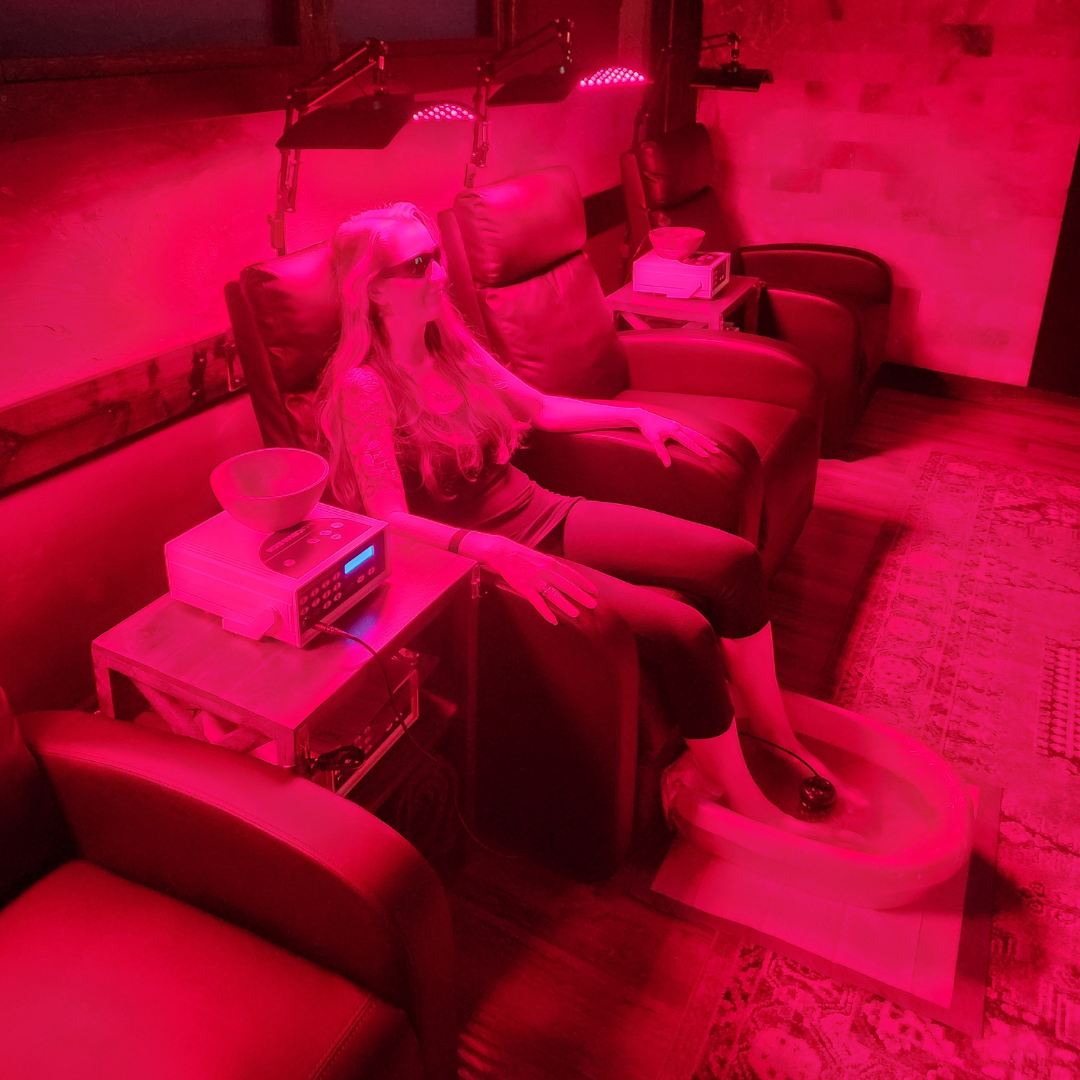 A woman is sitting in a chair under a red light.