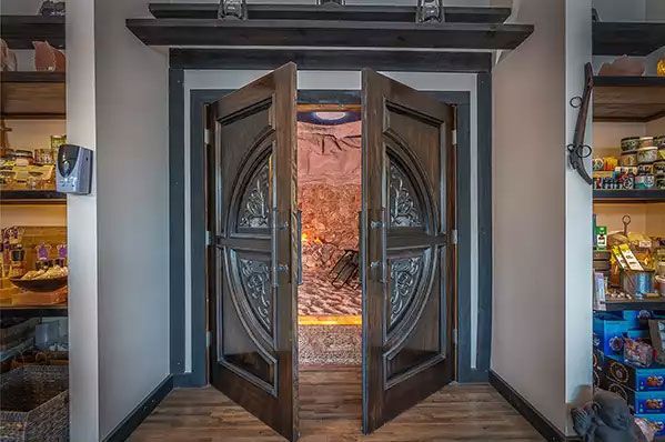 A large wooden door is open in a room with shelves.