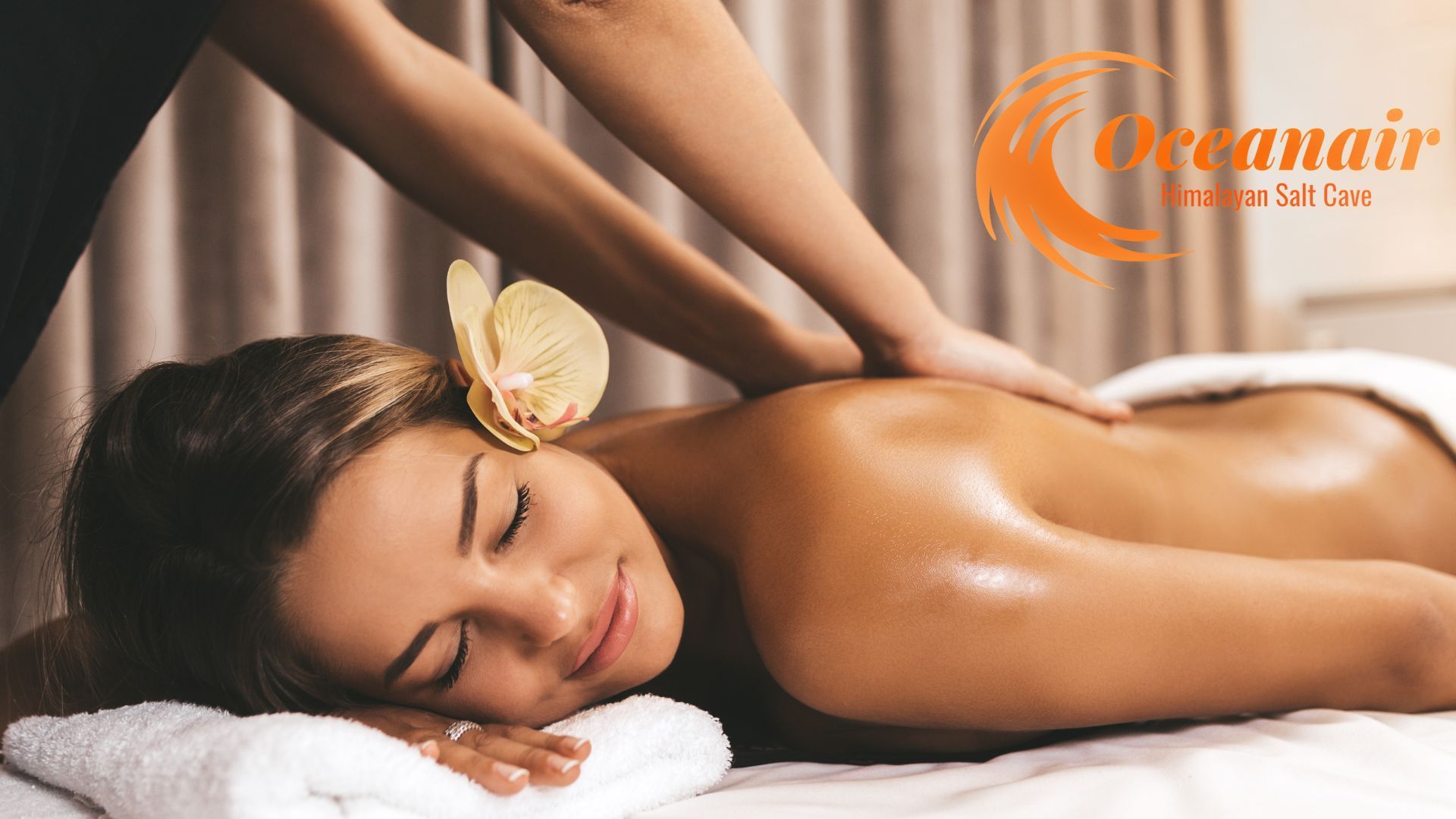 Woman receiving a back massage at a spa, with a flower in her hair.