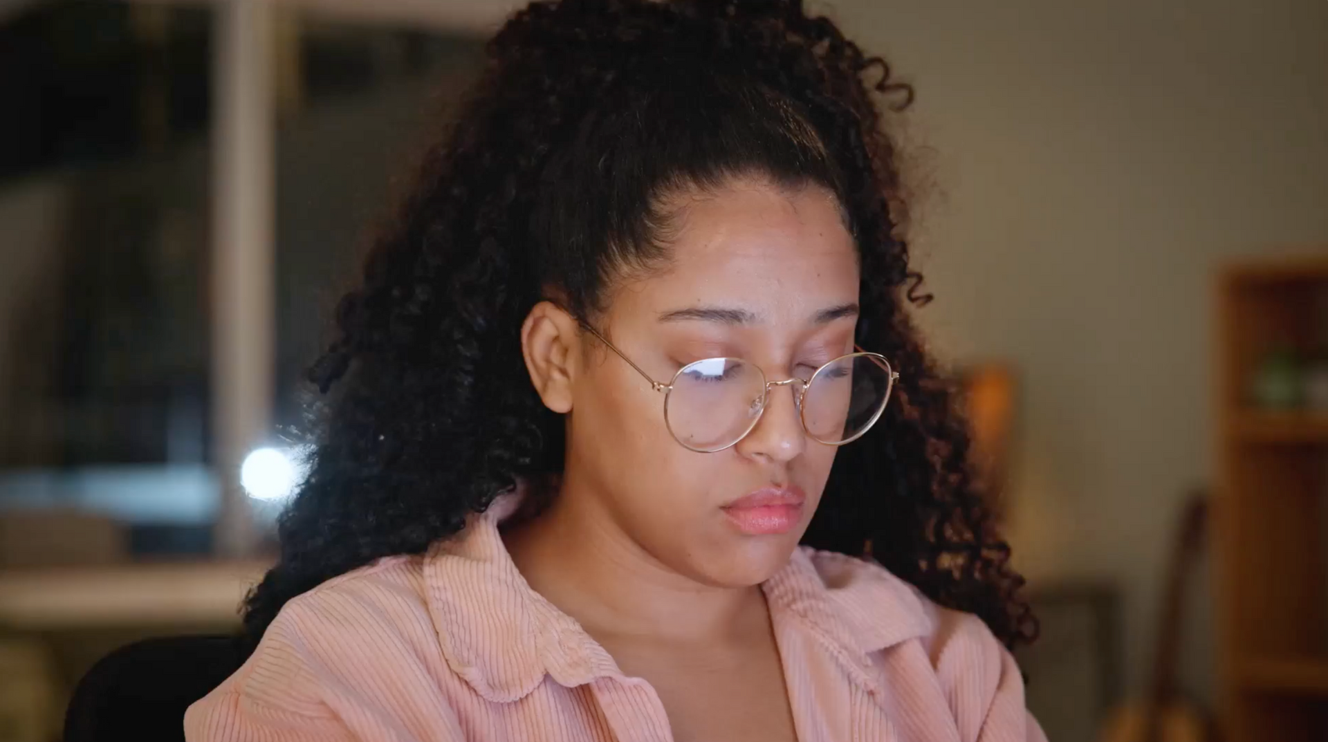 A woman wearing glasses is sitting in front of a computer screen.