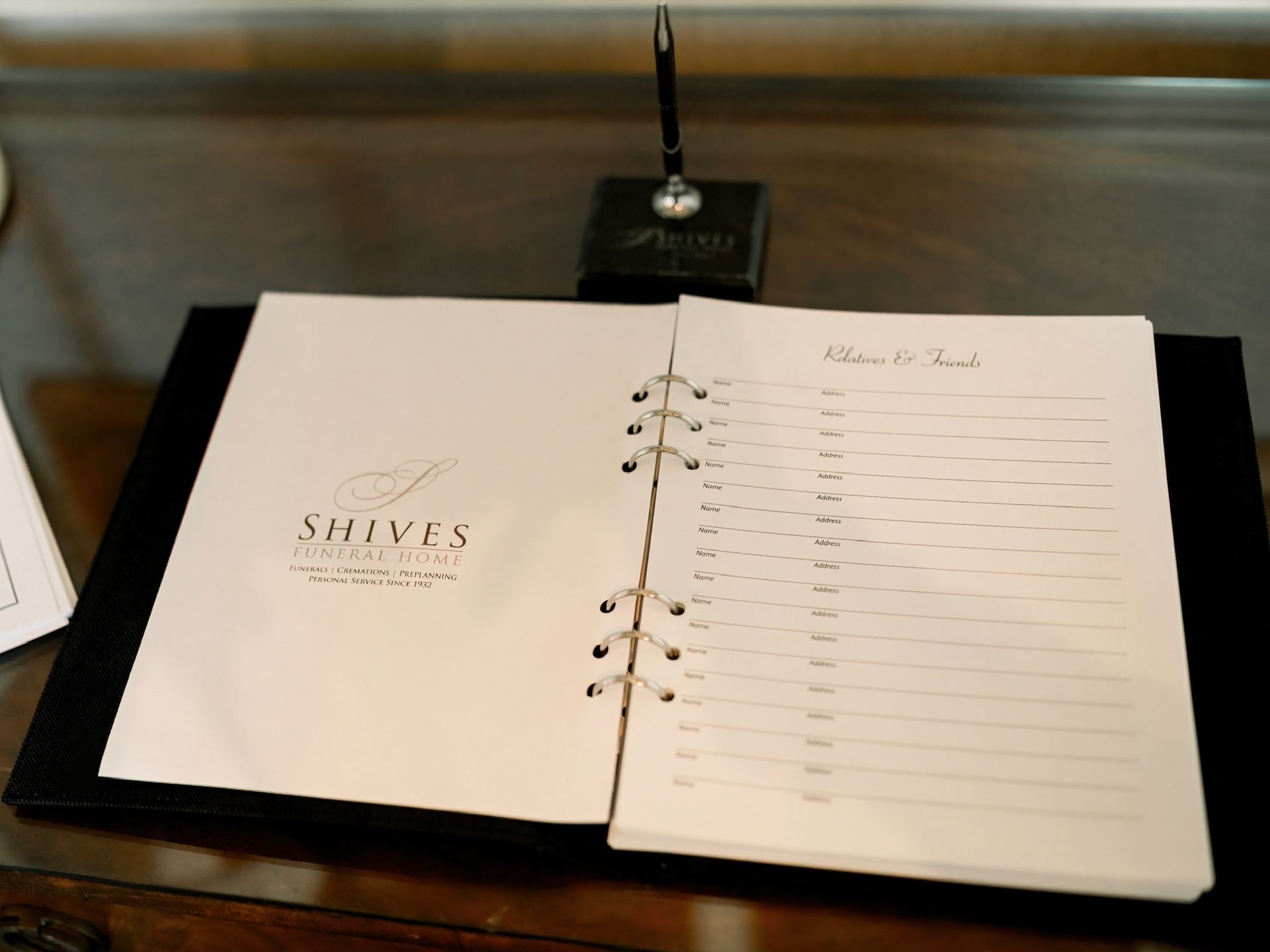 A person is typing on a laptop computer while holding a cell phone.