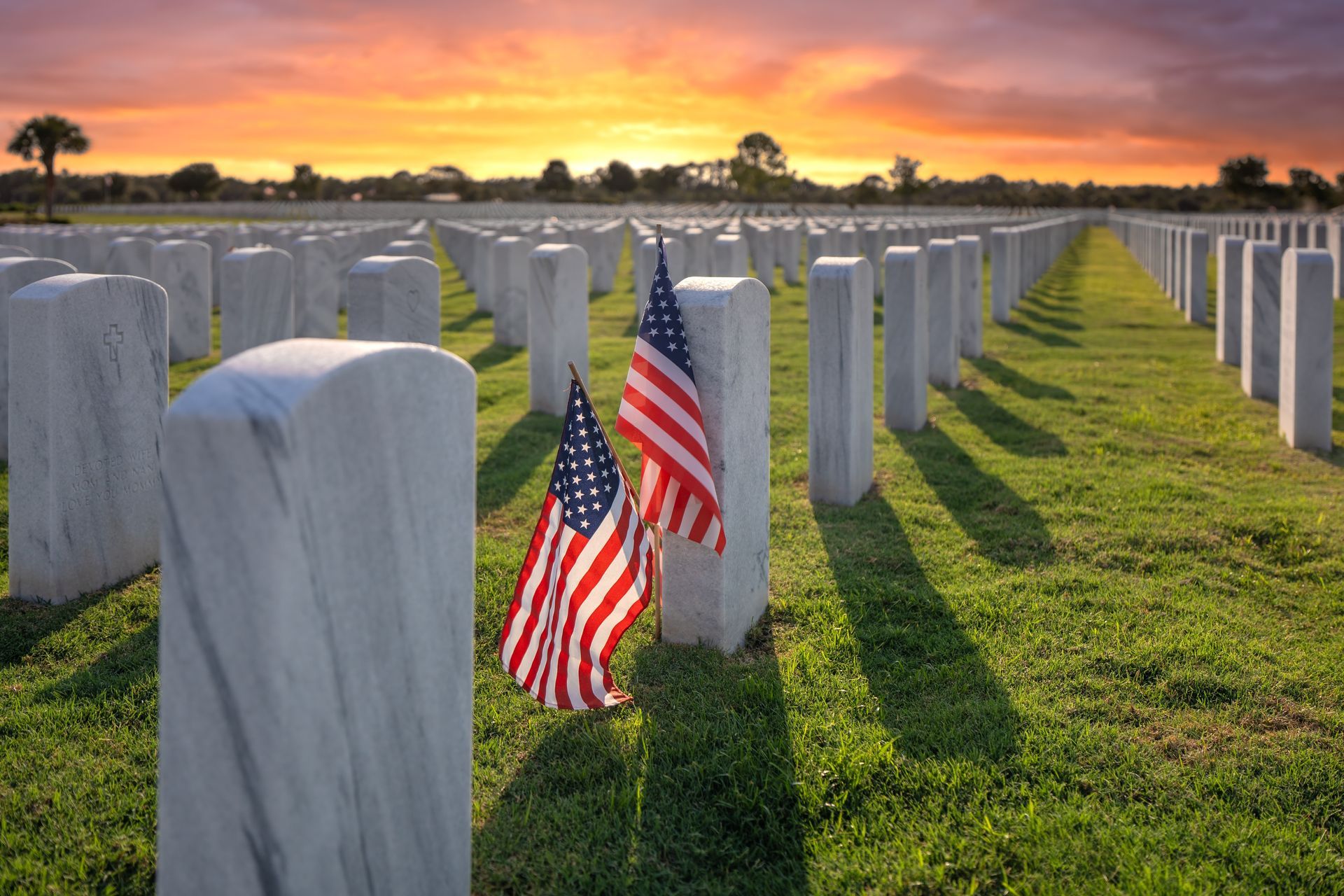 A man is holding an american flag over a coffin at a funeral.