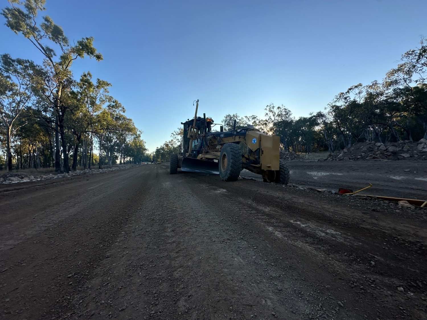 A Bulldozer Is Driving Down a Dirt Road  — L&V Civil Contracting in Park Ridge, QLD