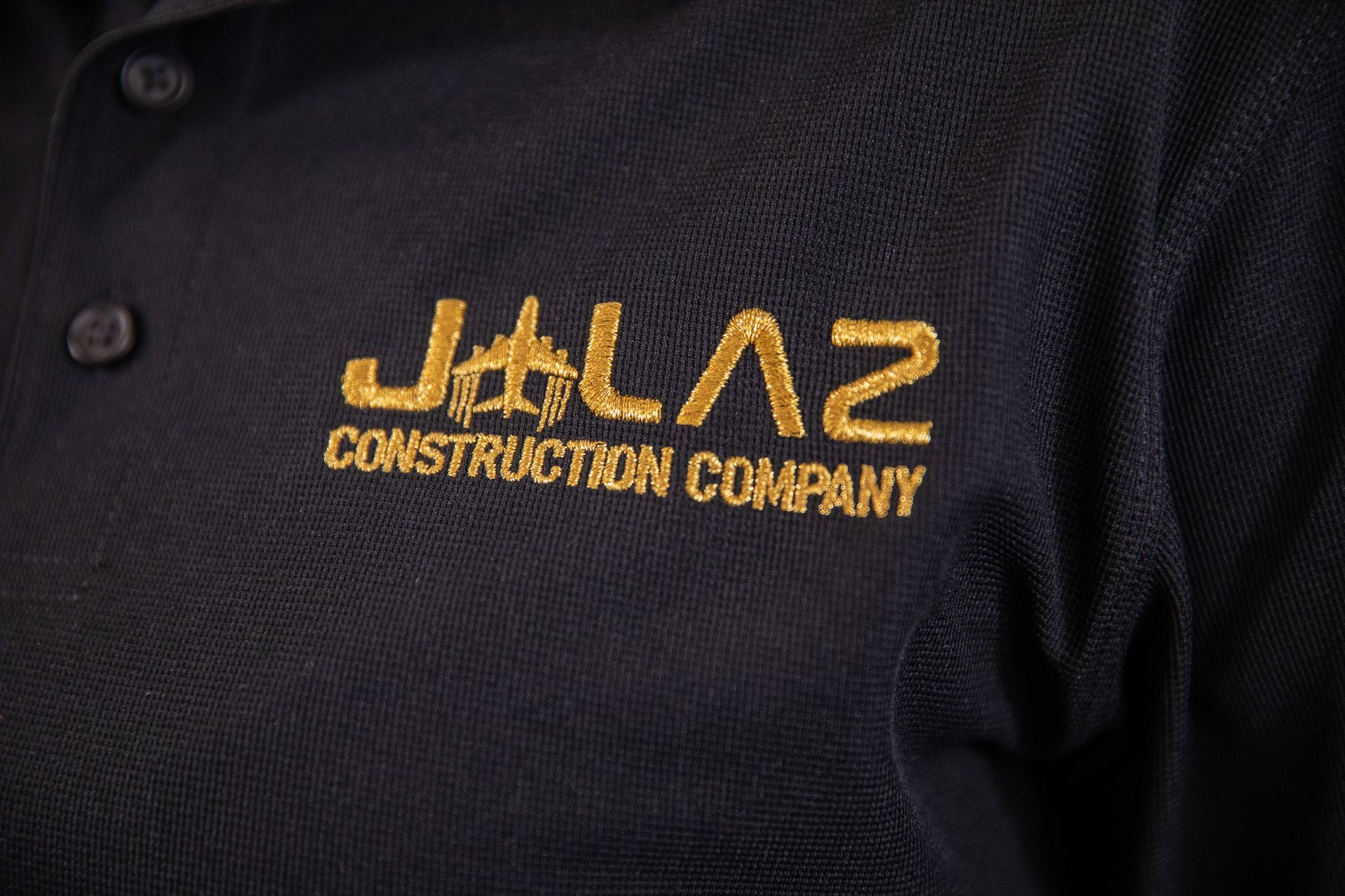 A black polo shirt with jalal construction company embroidered on it