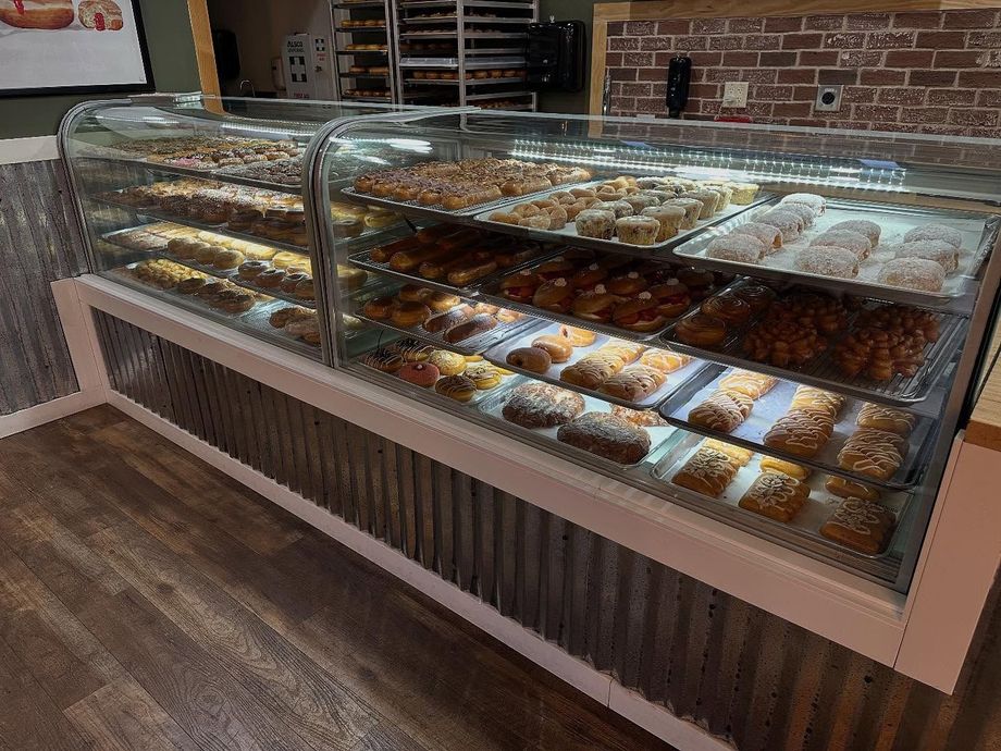 A display case filled with various donuts in a bakery setting.