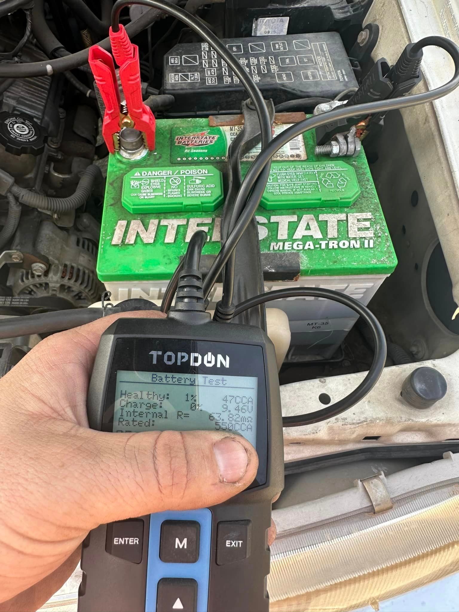 Person Is Holding A Tool In Front Of A Car Battery — Tempe, AZ — Precision Roadside Service