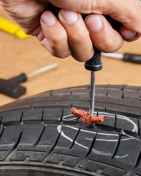 A Person Is Fixing A Tire With A Screwdriver — Tempe, AZ — Precision Roadside Service